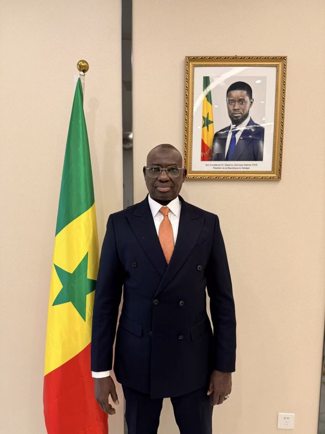 Monsieur Adama Dieye, Consul Général de la République du Sénégal à Guangzhou, devant le drapeau national et le portrait officiel du Président de la République